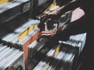Des mains parcourant des vinyles sur un étalage